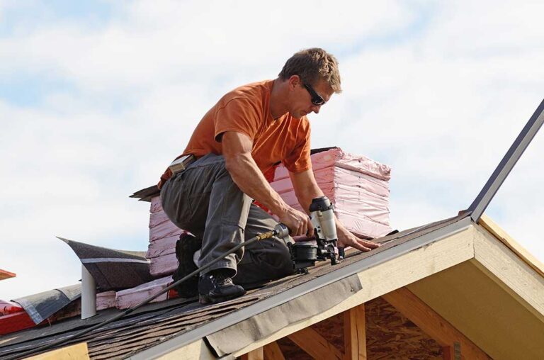 Homeowner inspecting a roof leak near a ceiling stain while a ladder and roofing tools rest nearby.